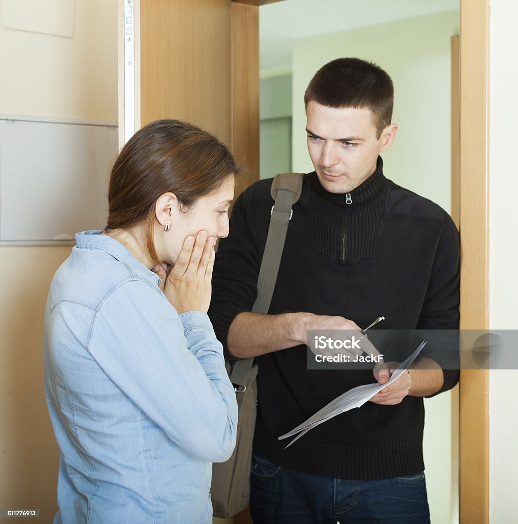 businessman trying to collect money from housewife businessman trying to collect money from housewife at home door. Focus on woman Confiscated Stock Photo