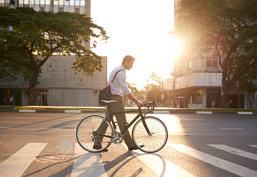 Shot of an attractive young man pushing his bicycle on the way to work