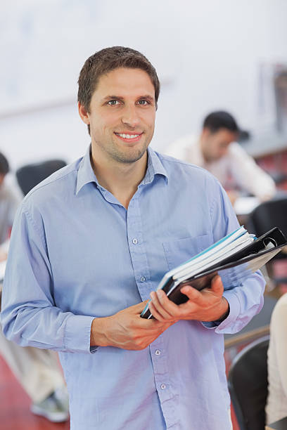 istock Cute male teacher holding some files 511281781