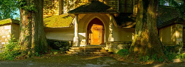 Portal of ancient abbey in Switzerland, Solothurn, with evening light. Two old lime trees border the portal's outer edges.