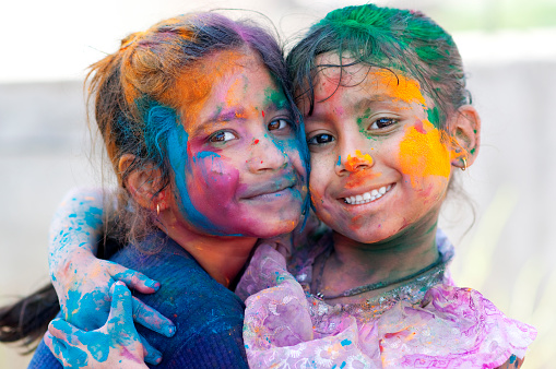Two little girls daubed in Holi colors shout as he enjoy the celebrations.