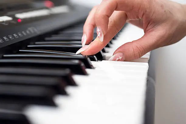 Photo of Woman hand playing a MIDI controller keyboard synthesizer close up