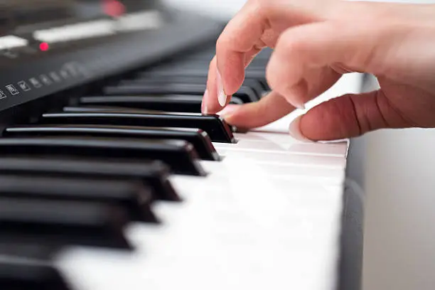 Photo of Woman hand playing a MIDI controller keyboard synthesizer close up