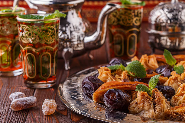Moroccan mint tea in the traditional glasses with sweets. Moroccan mint tea in the traditional glasses with sweets, selective focus. date syrup stock pictures, royalty-free photos & images