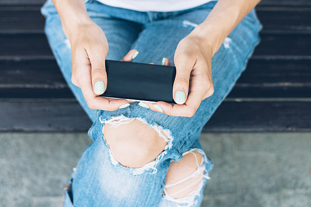 istock Girl in torn jeans sitting on a bench 511310514