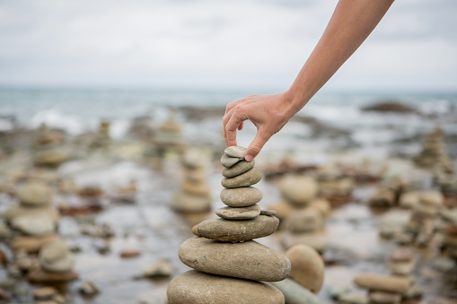 Detail of person stacking rocks by the sea. Cloudy day, Australia.