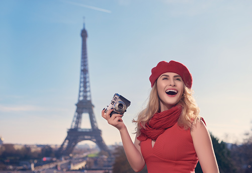 portrait of attractive blond hair woman in her city break in Paris holding vintage camera and creating new memories for a lifetime.