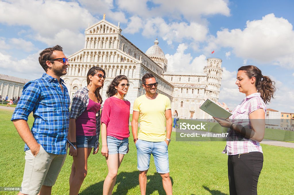 Group of tourists in Pisa, Italy Group of tourists in Pisa, Italy. A group of friends is listening to a guide talking about a famous monument. They are two women and two men wearing summer clothes. They are a multicultural group on holidays. Guide - Occupation Stock Photo