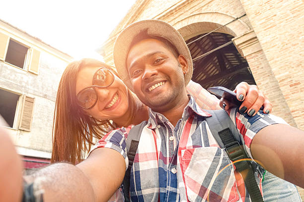 Multiracial travel couple taking selfie and having fun