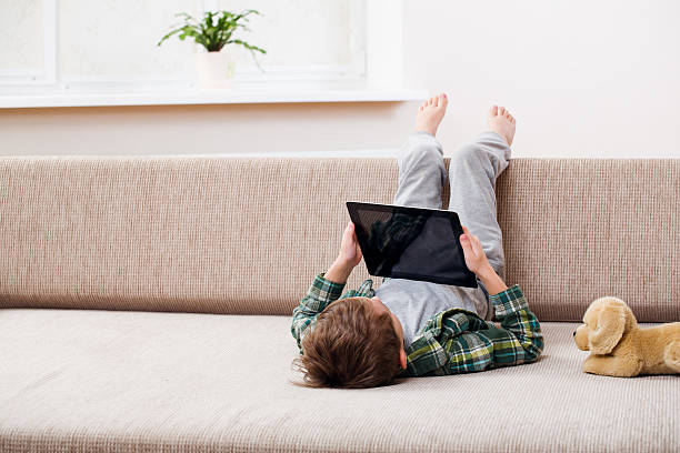 chłopiec bawi się z tablet - sofa indoors childhood technology zdjęcia i obrazy z banku zdjęć