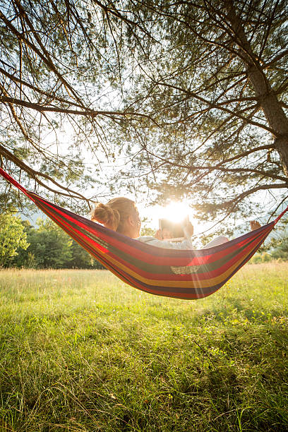 istock Woman on hammock at sunset relaxing with digital tablet 511321267
