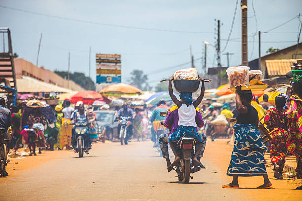 West African market scene. Bohicon, Benin - September 8, 2012: People crossing the street in busiest market junction in town, lot of motorbikes in background. benin stock pictures, royalty-free photos & images