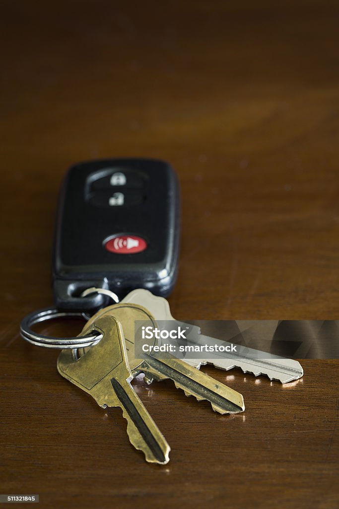 Key fob for a car and house keys on a table A close-up shot of a remote key fob or an automobile and three metal door keys on a key ring. Brass Stock Photo