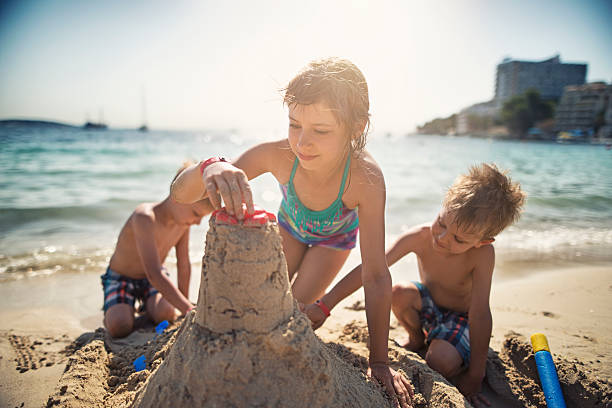 istock Brothers and sister building a sandcastle on beautiful beach 511322596