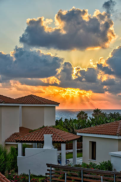 Sunset with sunbeams over luxurious holiday beach villas for rent on Cyprus