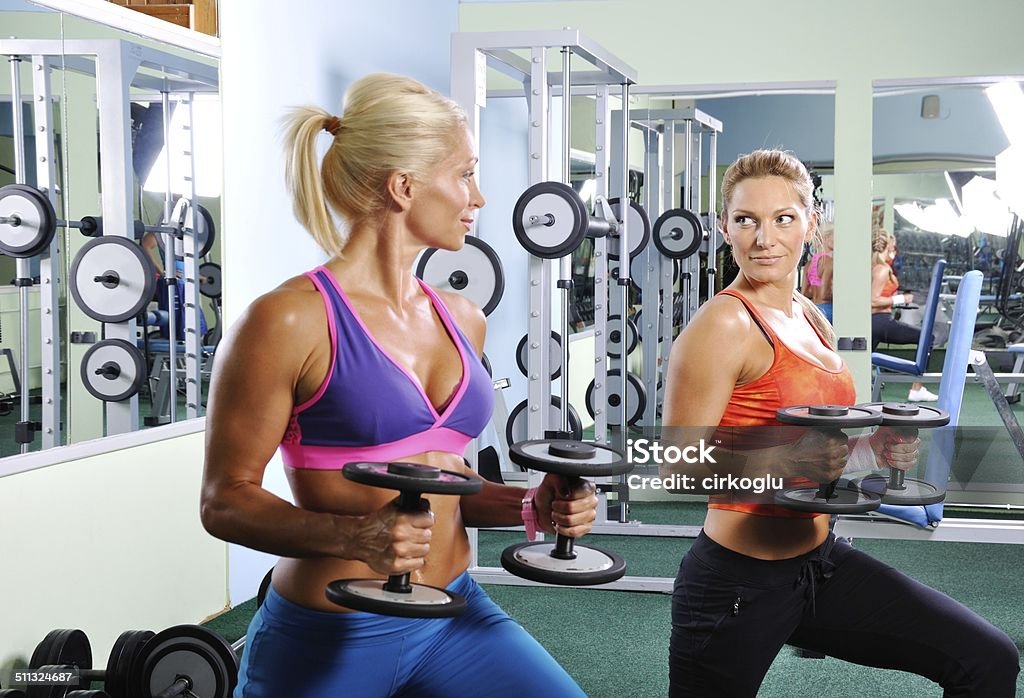 Two beautiful women exercising in gym with weights Activity Stock Photo