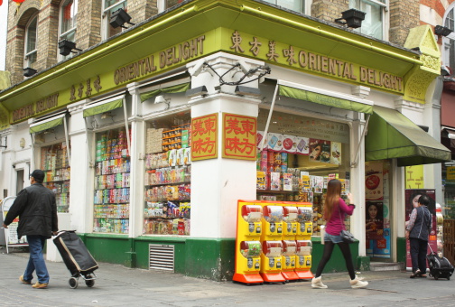 London, England - Sept 4th, 2014: People passing by the Oriental Delight supermarket in London's Chinatown District. The Chinese community of restaurants and businesses relocated here in the 1950s