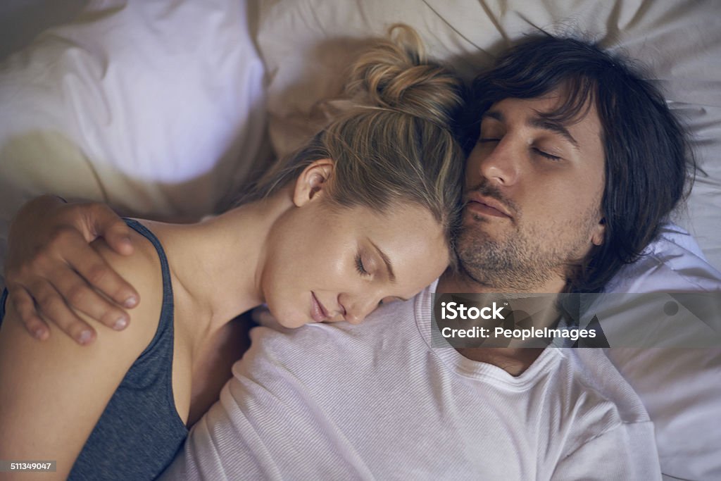 Safe in his arms Cropped shot of a young woman sleeping on her boyfriend's shoulder in bed 20-24 Years Stock Photo