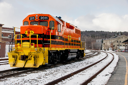 White River Junction, VT, USA-Feb. 11, 2016: A large diesel engine from the Connecticut Southern Railroad sits at the White River Junction in Vermont waiting to be hooked up to freight cars. The scene shows snow on a cold winter day. The engine is painted bright orange.