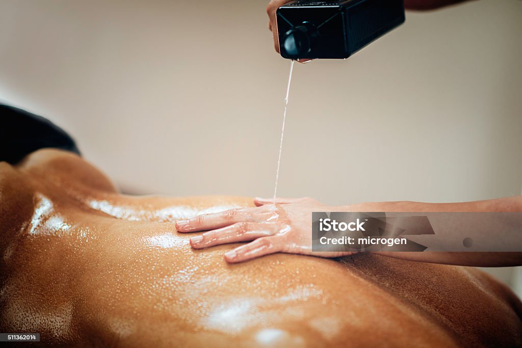 Sports massage Sports massage. Physical therapist putting massage oil Massaging Stock Photo