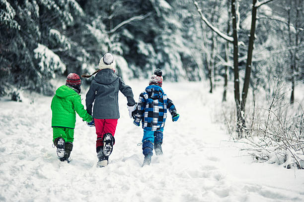 Three kids running in winter forest Three kids running in cold winter forest. The little girl is aged 10 and her brothers are aged 6. Back view. kids winter coat stock pictures, royalty-free photos & images