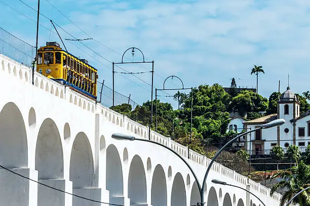 Train drives along distinctive white arches of the landmark Lapa Arches (Carioca Aqueduct) in Rio de Janeiro, Brazil