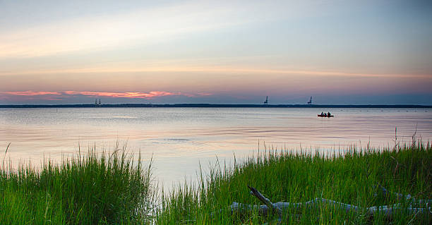 Sunset Canoe August 14, 2015 Fort Fisher Air Force Recreation Center, Kure Beach, North Carolina, USA: A family views the sunset from a canoe on the Cape Fear River. cape fear stock pictures, royalty-free photos & images