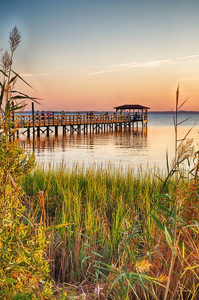 Cape Fear River The pier on the Fort Fisher Recreation Area near Kure Beach, North Carolina with the sunsetting in the distance. cape fear stock pictures, royalty-free photos & images
