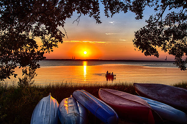 sunset Canoe August 14, 2015 Fort Fisher Air Force Recreation Center, Kure Beach, North Carolina, USA: A family views the sunset from a canoe on the Cape Fear River. cape fear stock pictures, royalty-free photos & images