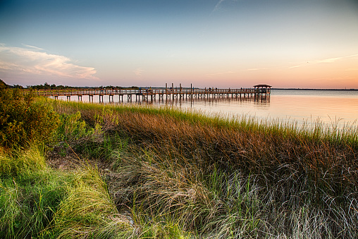 The pier on the Fort Fisher Recreation Area near Kure Beach, North Carolina with the sunsetting in the distance.
