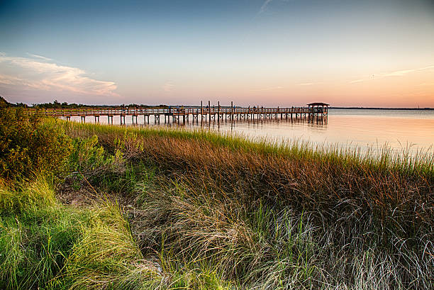 Cape Fear River The pier on the Fort Fisher Recreation Area near Kure Beach, North Carolina with the sunsetting in the distance. cape fear stock pictures, royalty-free photos & images