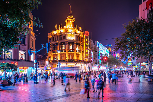 Crowds walk below neon signs on Nanjing Road. The street is the main shopping district of the city and one of the world's busiest shopping districts. 