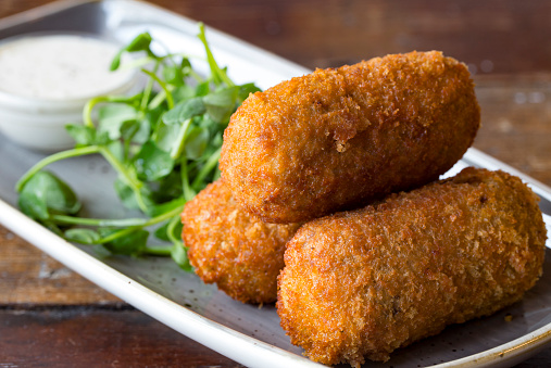 Three small breadcrumbed fried food roll containing, mashed potatoes with fish, meat or vegetables 