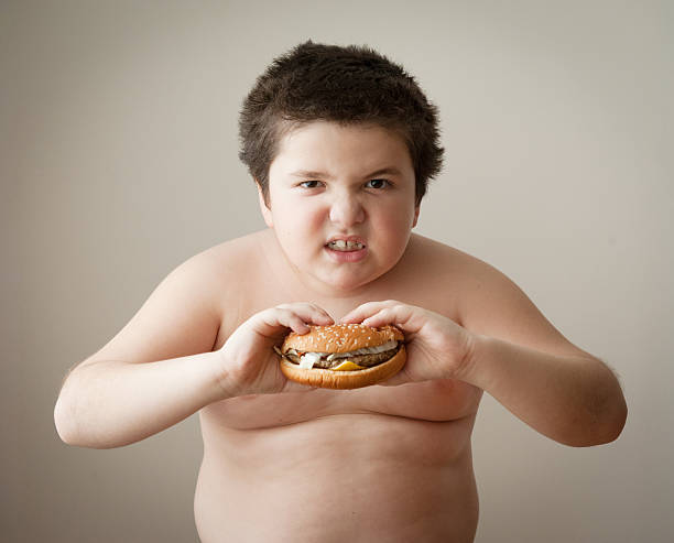 人少年のお子様には、チーズバーガー、脂肪ブルジェのお食事 - overweight child eating hamburger ストックフォトと画像