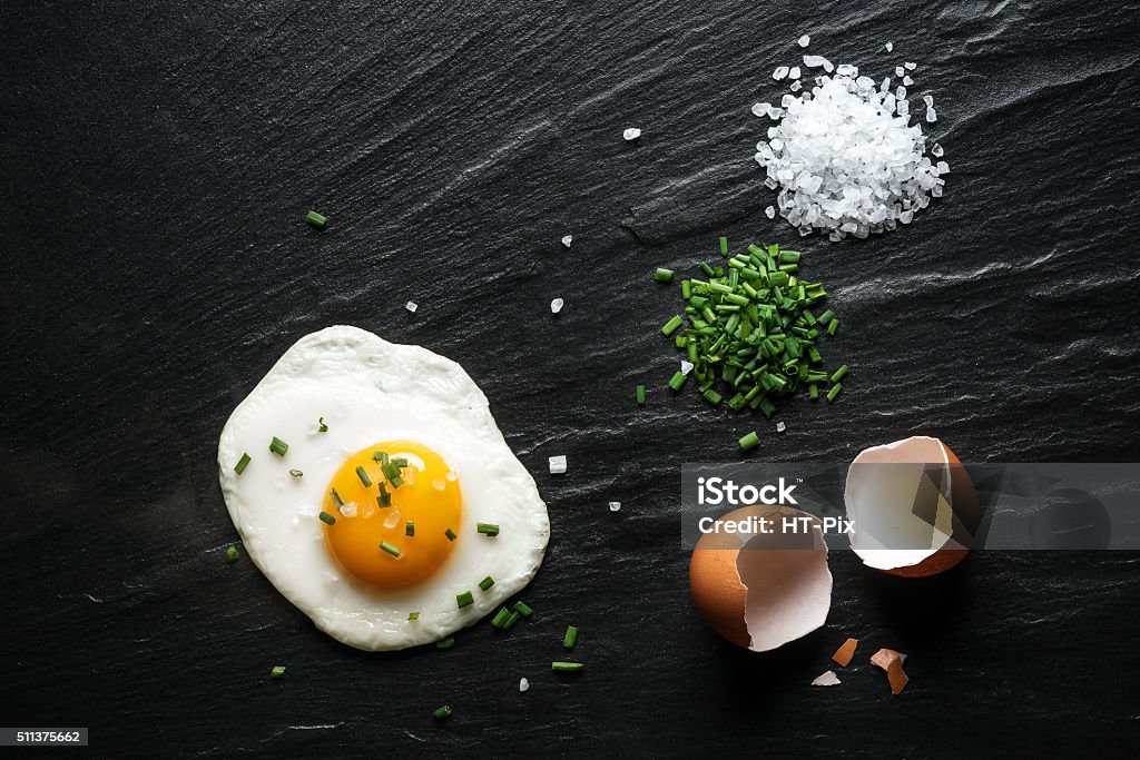 Breakfast, Fried Egg on a Slate Fried egg on a slate with chives and coarse sea salt . Fried Egg Stock Photo