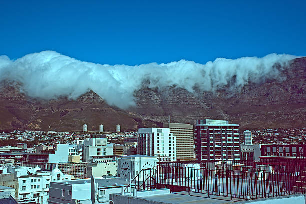 Retro-styled View of Table Mountain South Africa With Tablecloth Cityscape of Cape Town, South Africa facing Table Mountain. Table Mountain has characteristic "tablecloth" cloud cover for which it's named. The styling is like old slide film. table mountain and the tablecloth stock pictures, royalty-free photos & images