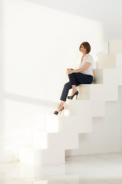 istock Elegant adult woman smiling while sitting on steps 511379744