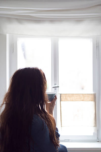 istock Young women at window drink tea 511381386