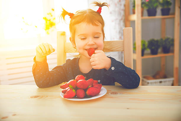 istock happy child girl eats strawberries in summer home kitchen 511382268