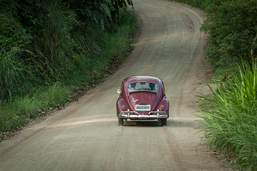 Pomerode, Santa Catarina, Brasil - May 28, 2011: View of two people inside a car driving on a dirt road surrounded by nature in the countryside of Pomerode city located in Santa Catarina state, Brazil