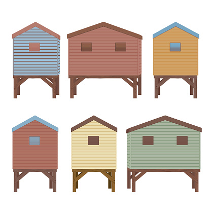 Pastel colored wooden beach huts. The huts are all on wood stilts and have ship lap sided walls. Back view.