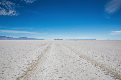 Car Tire Track to the horizon under blue sky in the Salt Flats Desert close to Bonneville, Salt Lake City, Utah, USA.