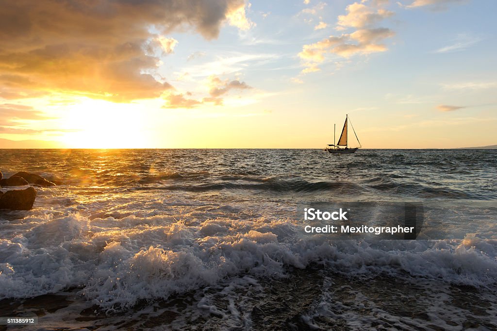 Sailboat Sunset Sailboat Sunset is a sailboat with people aboard close to shore with a rough wave rolling in and the sun setting on the ocean horizon. Rough Stock Photo