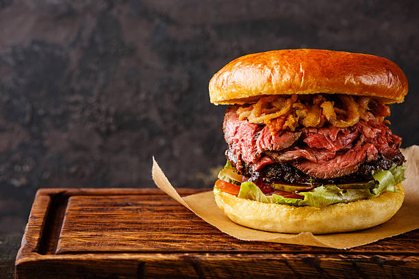 Pastrami Burger with sliced Roast beef and onion fries rings Pastrami Burger with sliced Roast beef and onion fries rings on black background pastrami stock pictures, royalty-free photos & images