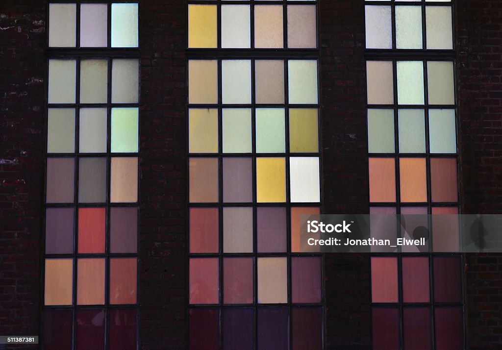Multicolored window panes in brick wall Various colored backlit window panes in a brick wall Brick Stock Photo