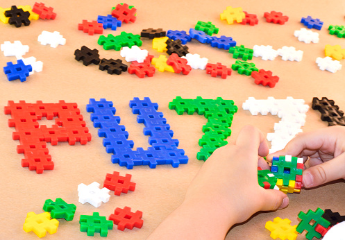 Little boy is playing with his puzzles. Isolated on background with word puzzle