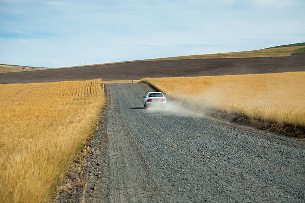 istock White car throwing up dust cloud on gravel farm road 511387715