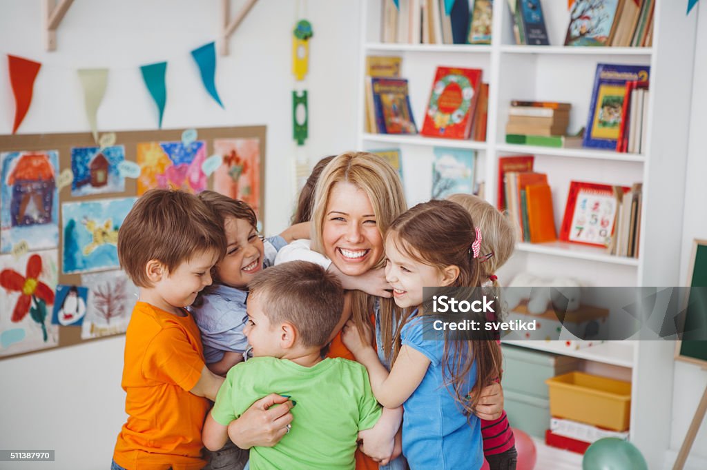 We love our teacher Kids in kindergarden playing with their teacher.They are hugging her to express their love. Teacher Stock Photo
