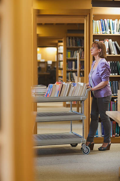 istock Serious female librarian pushing a cart 511388765