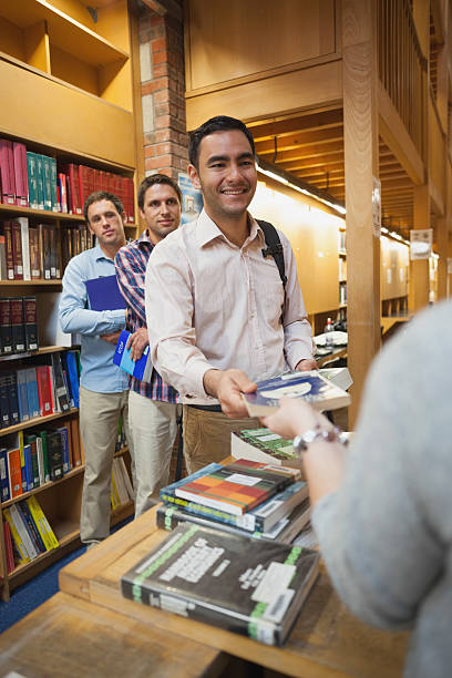 istock Attractive man handing a book to the female librarian 511388865